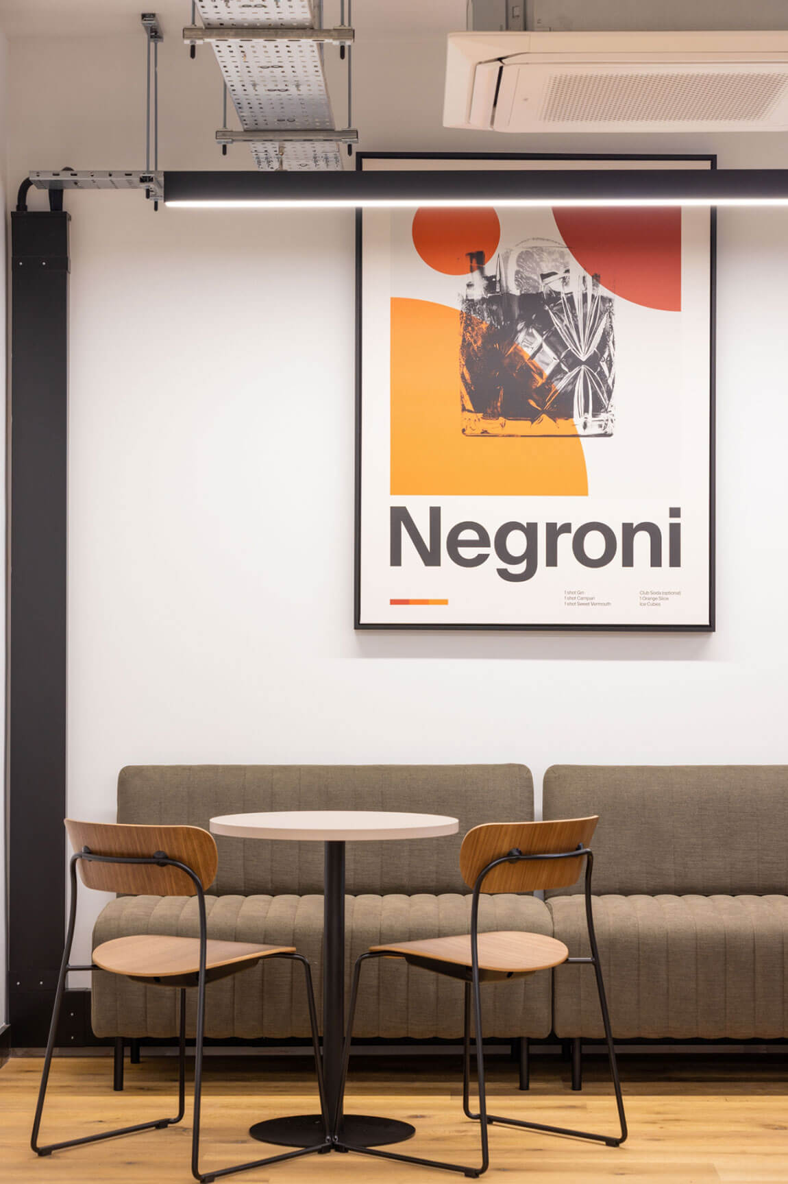 Breakout seating area with a sofa, cafe table and a framed Negroni cocktail print